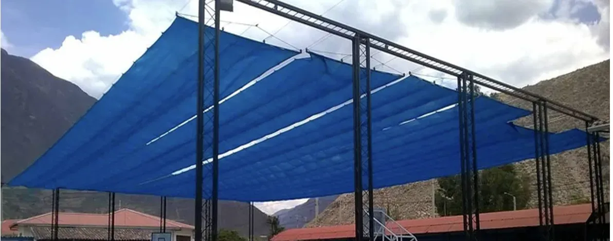 Estructura metálica con cubierta textil tensada azul sobre una pista deportiva