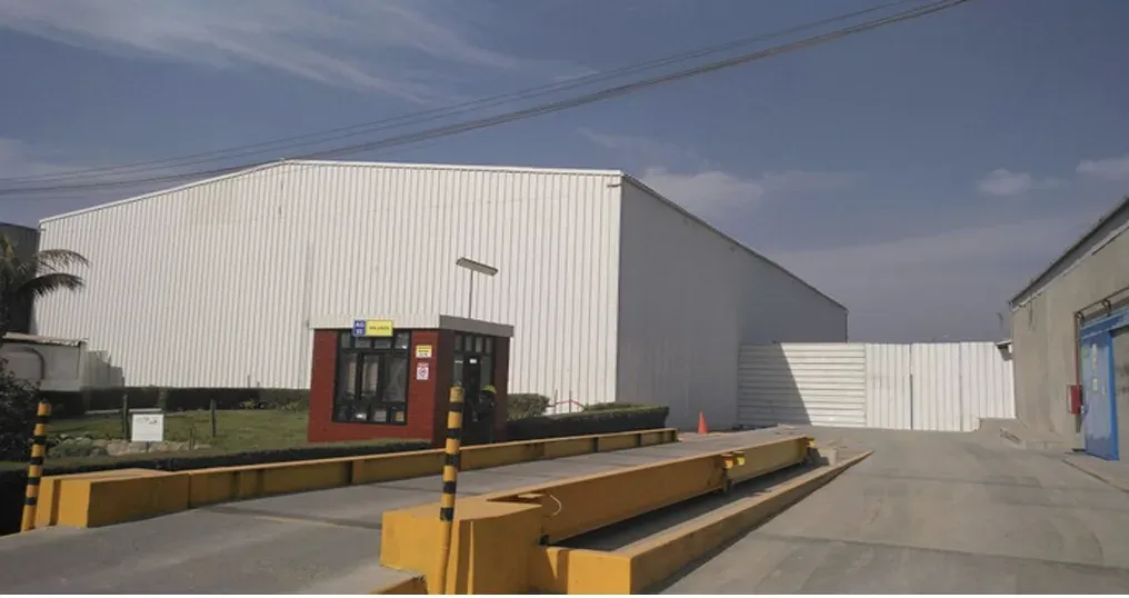 Nave industrial con cerramiento de chapa metálica blanca y control de acceso en la entrada